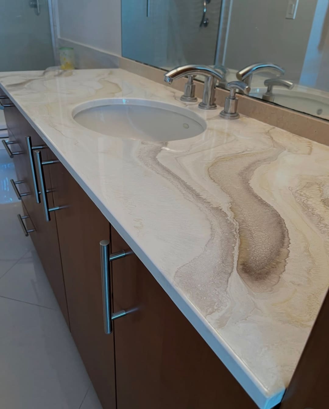 A bathroom vanity with a cream and tan marble look epoxy countertop poured around the sink
