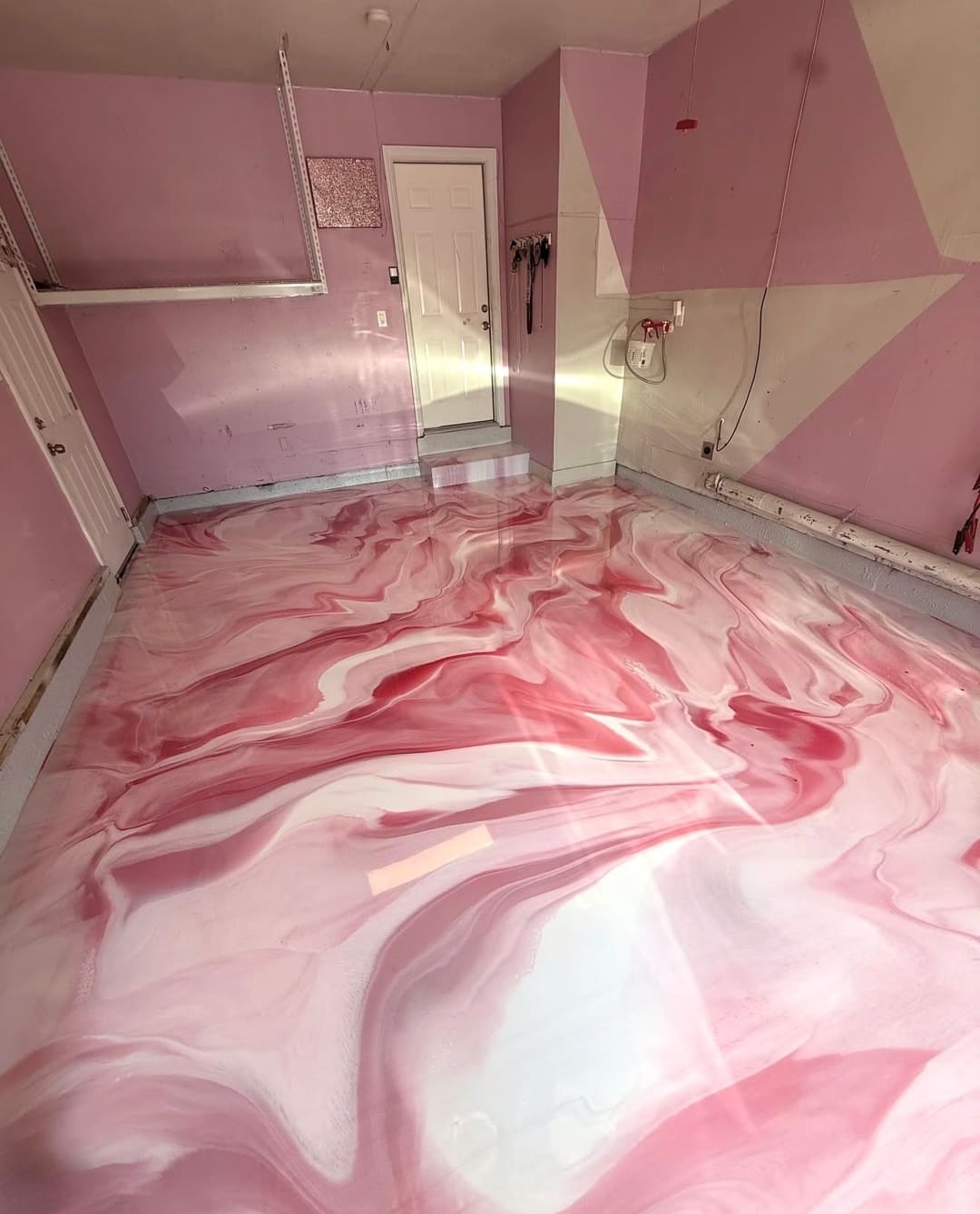 A pink and white marbled metallic epoxy floor running wall to wall in a pink room