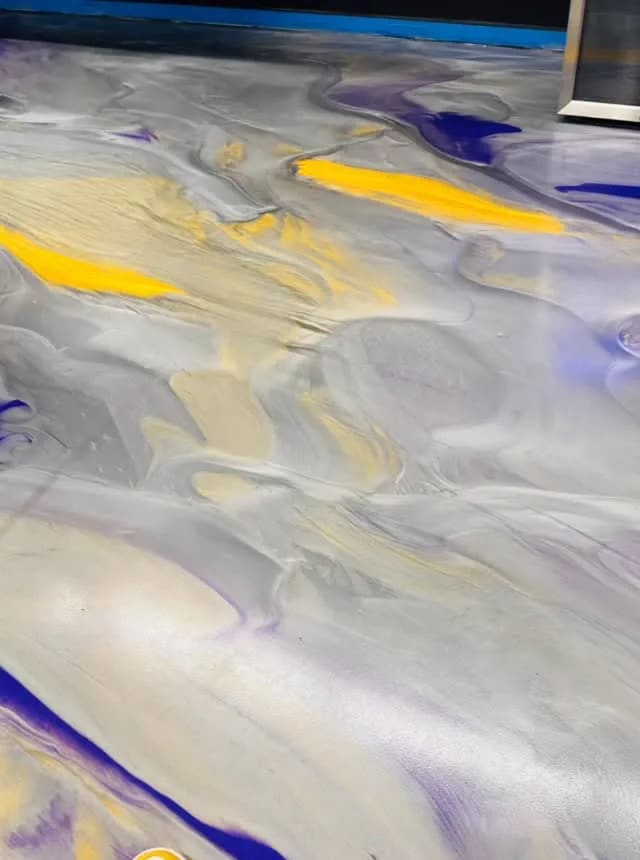 A silver metallic epoxy floor marbled with purple and bright yellow streaks